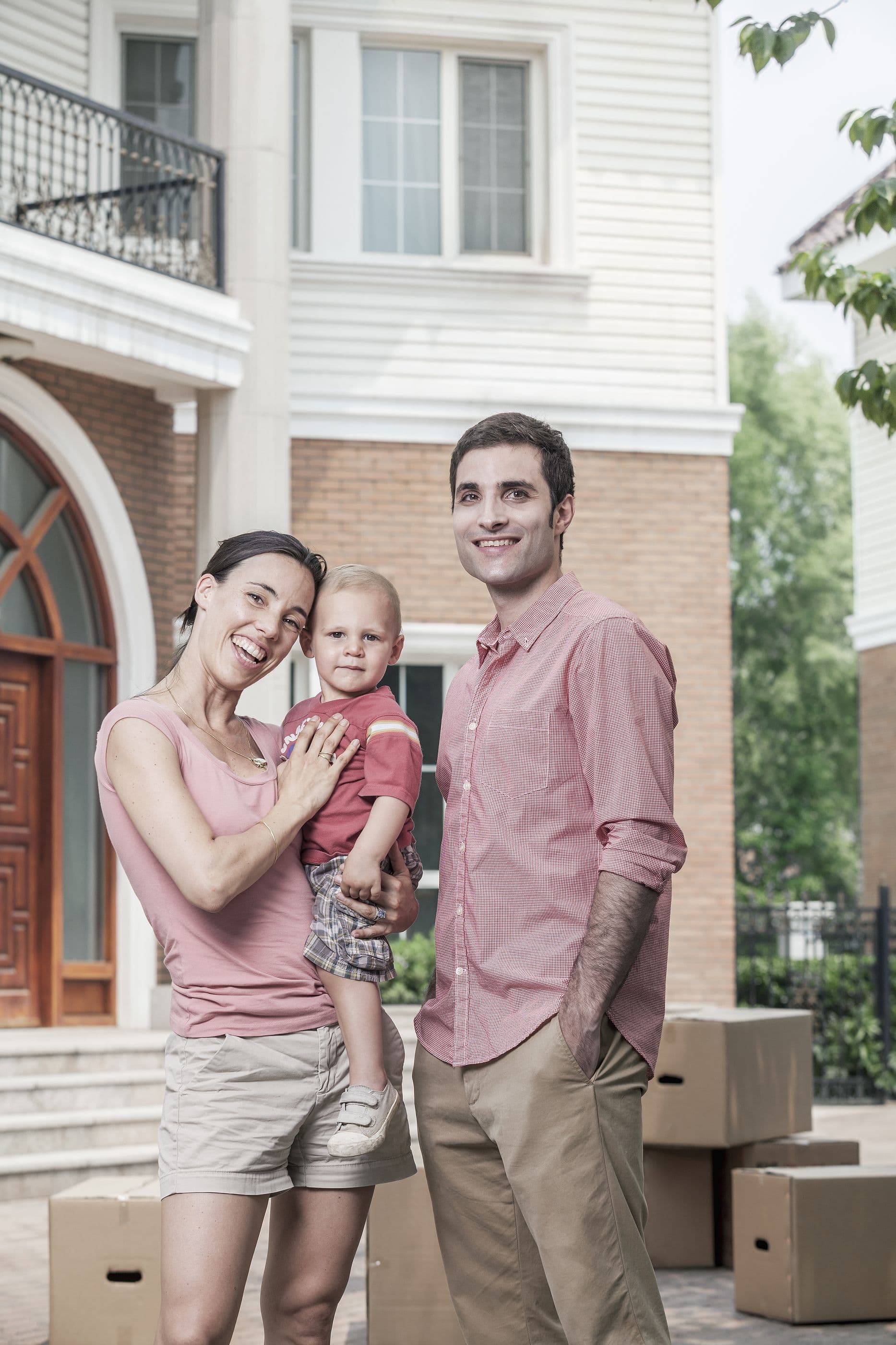 Family smiling in front of house