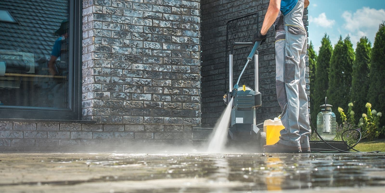 man pressure washing sidewalk cropped